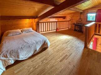 Experience rustic charm in this cozy loft bedroom, featuring a comfortable bed with plush pillows and a warm, wood-paneled ambiance.