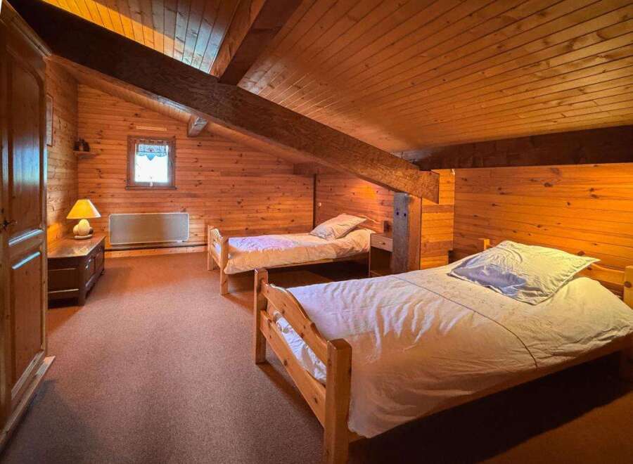 This charming attic bedroom features two cozy single beds, perfect for guests or family.