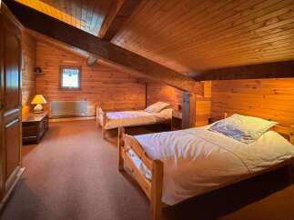 This charming attic bedroom features two cozy single beds, perfect for guests or family.