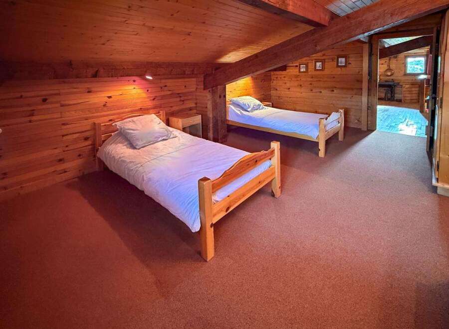 This charming attic bedroom features two cozy wooden twin beds, perfect for a family or guests.