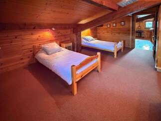 This charming attic bedroom features two cozy wooden twin beds, perfect for a family or guests.