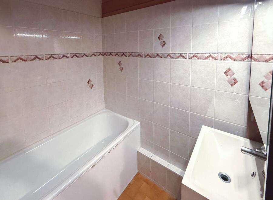 This bathroom features a pristine white bathtub and a modern sink, perfect for a relaxing soak or a quick refresh.