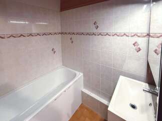This bathroom features a pristine white bathtub and a modern sink, perfect for a relaxing soak or a quick refresh.