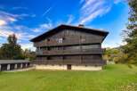 Experience alpine living in this charming wooden chalet-style building, featuring multiple balconies and a classic pitched roof.