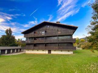 Experience alpine living in this charming wooden chalet-style building, featuring multiple balconies and a classic pitched roof.