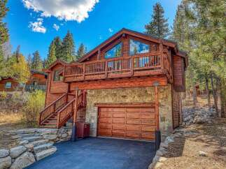 Experience mountain living in this stunning wooden home, featuring a spacious deck with panoramic views and a rustic stone-accented lower level.