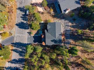 Discover this stunning property featuring a modern dark shingle roof and expansive wooden decks, perfect for outdoor entertaining.