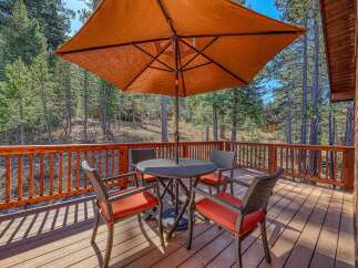 Enjoy the outdoors on this charming wooden deck, perfect for al fresco dining or relaxing with a view of the surrounding pine forest.