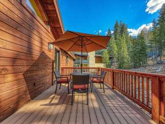 Enjoy your morning coffee or evening drinks on this charming wooden deck, complete with a table, chairs, and a large umbrella for shade.