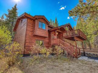Experience the charm of this rustic wooden cabin nestled amidst tall pine trees.