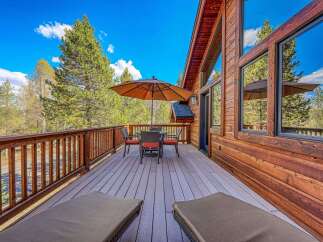 Enjoy the outdoors on this spacious wooden deck, complete with comfortable lounge chairs and a dining set under a large umbrella.