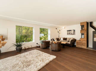 Experience modern living in this spacious living room, featuring large windows that flood the space with natural light and offer picturesque views of the surrounding greenery.