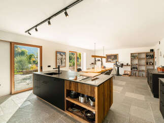 Experience modern living in this spacious open-plan kitchen and dining area, featuring a sleek black island with integrated sink and a rustic wooden base.