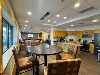 This spacious common area features a modern kitchen with ample cabinet space, granite countertops, and stainless steel appliances, perfect for preparing meals.