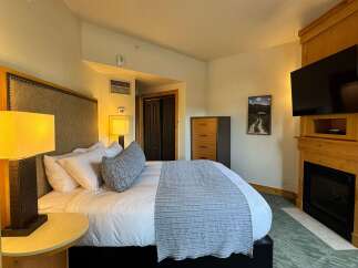 Experience ultimate comfort in this beautifully appointed hotel room, featuring a plush king-sized bed with crisp white linens and a decorative throw.