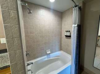 This hotel bathroom features a clean and spacious bathtub with a tiled surround.