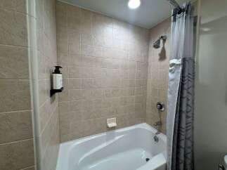 Step into this beautifully tiled bathroom, featuring a pristine white bathtub perfect for relaxing soaks.
