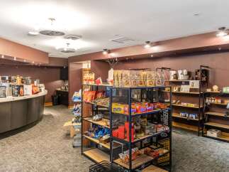 Discover a charming retail space featuring a well-appointed coffee bar with a variety of latte flavors and a curated selection of snacks and pantry staples.