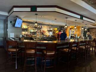 Experience the inviting ambiance of this well-appointed bar, featuring a sleek metallic counter and comfortable leather bar stools perfect for socializing.
