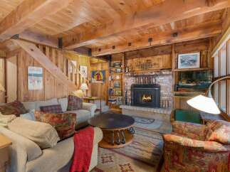 Cozy up by the fireplace in this rustic living room, featuring exposed wooden beams and a warm, inviting atmosphere.