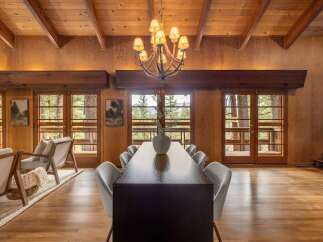 Experience rustic charm in this spacious dining area, featuring a large wooden table surrounded by comfortable grey chairs, perfect for family gatherings.