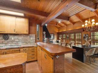 Experience rustic charm in this open-concept living space, featuring a warm wood-paneled interior with exposed beams and a vaulted ceiling.
