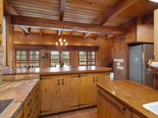 Experience rustic charm in this spacious kitchen, featuring warm wooden cabinetry and exposed beams that create a cozy, cabin-like atmosphere.