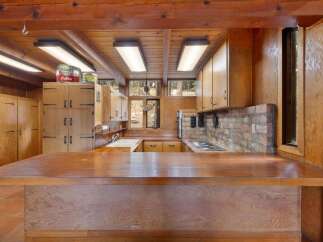 Step into a charming rustic kitchen featuring warm wood cabinetry and exposed wooden beams.