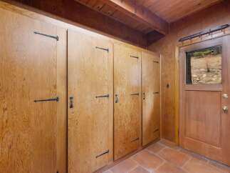 Discover ample storage solutions with this charming built-in cabinetry, featuring rustic wooden doors and decorative black hardware.