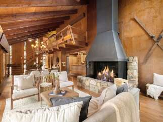 Experience rustic charm in this spacious living area, featuring a grand stone fireplace and exposed wooden beams that create a warm, inviting atmosphere.