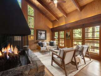 Experience cozy living in this rustic mountain retreat, featuring a grand stone fireplace and soaring vaulted wood-paneled ceilings.