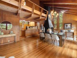 Experience rustic charm in this spacious living area featuring a dramatic vaulted ceiling with exposed wooden beams and a striking black fireplace as the focal point.