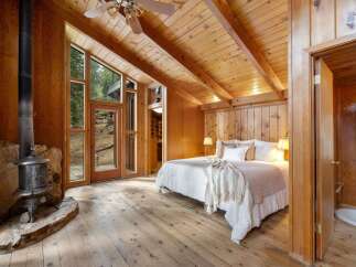 Experience rustic charm in this cozy bedroom featuring a striking wood-burning stove set against a natural stone hearth.
