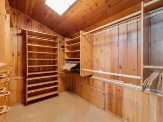 Discover ample storage in this spacious walk-in closet, featuring extensive shelving and multiple hanging rods.