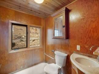 This rustic bathroom features warm wood paneling on the walls and ceiling, creating a cozy cabin feel.
