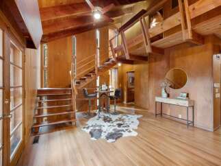 Step into a warm and inviting living space featuring rich wood paneling and exposed beams, creating a cozy, rustic ambiance.