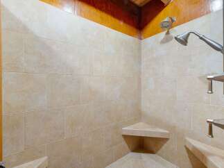 Step into this luxurious shower featuring elegant beige tiled walls and a built-in corner bench for ultimate relaxation.