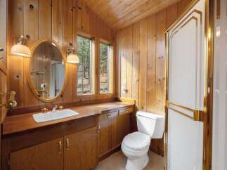 This charming bathroom features warm wood paneling throughout, creating a cozy cabin-like atmosphere.