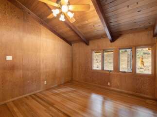This charming room features warm wood-paneled walls and a vaulted wood-beamed ceiling, creating a cozy and rustic ambiance.