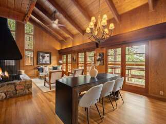 Experience rustic charm and modern comfort in this stunning living space, featuring a grand stone fireplace and soaring vaulted ceilings with exposed wooden beams.