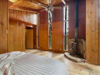 Experience rustic charm in this bedroom featuring warm wood paneling and a vaulted ceiling with a ceiling fan.