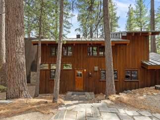 Nestled amongst towering pine trees, this rustic wooden home offers a serene escape.