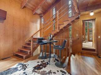 Experience rustic charm in this wood-paneled interior featuring a unique staircase and a cozy bar area.