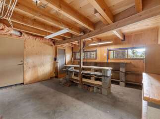 Discover a versatile workshop space with a durable concrete floor and exposed wooden beams, perfect for any project.