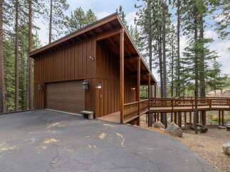 This charming wooden cabin features a spacious garage and an elevated wooden deck, perfect for enjoying the surrounding forest views.