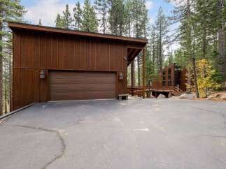 Nestled amongst tall pine trees, this modern mountain home features a striking wood-paneled exterior and a spacious two-car garage.