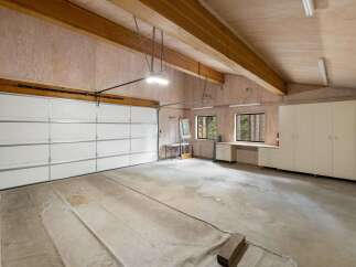 This spacious garage offers ample storage with a wall of tall cabinets and a built-in workbench.