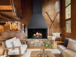 Cozy up by the stone fireplace in this rustic living room, featuring a striking black hood and a vintage barber pole accent.