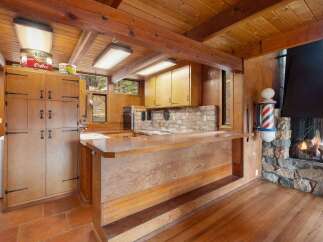 This rustic kitchen boasts a warm, wood-paneled aesthetic with exposed beams and a charming breakfast bar.