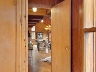 Step into a charming cabin-style living space featuring a vaulted wood-paneled ceiling with exposed beams and a rustic chandelier.